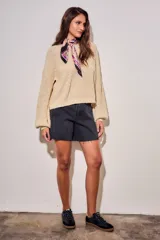 Sweater de tejido bouclé texturado color beige, con cuello redondo y mangas largas holgadas de corte amplio.