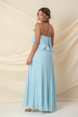 Vestido largo strapless de gasa plisada color celeste, con volados en el busto y corte en la cintura.