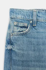 Jeans baggy de tiro medio con pernera holgada, diseño de cinco bolsillos y bajo acabado en vuelta. Cuenta con cintura elástica en la espalda y cierre frontal con cremallera y botón.