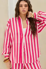 Camisa de corte oversize con estampado de rayas verticales en tonos fucsia y blanco, de manga larga abullonada y cierre frontal con botones.