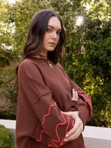 Buzo azul marino de tejido sin friza, con cuello redondo y bordados blancos con diseño de flores estilizadas en las mangas.