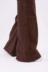 Jean wide-leg color marrón chocolate, con tiro medio, bolsillos frontales y traseros, y costuras decorativas verticales a lo largo de las piernas.