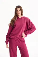 Buzo canguro deportivo de color bordó, sin friza, con capucha y detalles de tachas en las mangas.