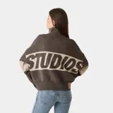 Buzo tejido de punto con cierre frontal completo, cuello tipo polo y diseño de bloques de color con logo EME tejido en jacquard. Presenta un corte holgado y ligeramente corto, con puños y ruedo acanalados.