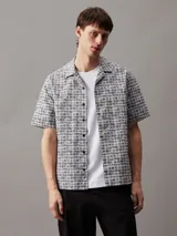 Camisa de hombre de manga corta con cuello cubano, corte boxy y estampado geométrico de rejilla en blanco y negro.