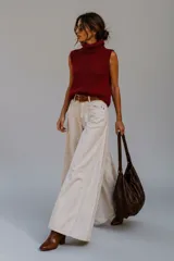 Pantalón de jean tiro alto con corte elefante, de color crudo, con costuras verticales marcadas en el frente y diseño de pierna ancha.