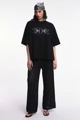 Remera blanca de corte boxy, cuello redondo a la base y mangas cortas. Presenta un pequeño estampado localizado en el centro del pecho que simula un ají en tono rojizo.