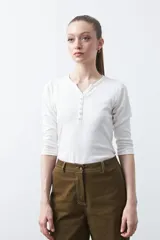 Remera de manga larga color blanco, confeccionada en algodón, con escote en V y cartera corta de botones.