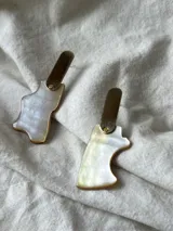 Par de caravanas colgantes con piezas irregulares de nácar y detalles en metal dorado.