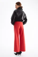 Jean rojo de tiro alto, corte wide leg y diseño tobillero, con bolsillos delanteros tipo parche con botón y pliegues marcados.