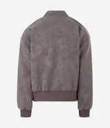 Campera de material sintético en color gris topo, con cuello inglés, cierre frontal por cremallera, mangas largas con puños elásticos y diseño de relieve tribal en la espalda.