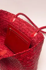 Bolso tipo tote de cuero vacuno, completamente trenzado a mano. El color es marrón oscuro, casi chocolate. Posee dos asas de hombro trenzadas.