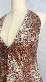 Vestido corto ajustado con escote profundo en V y cuello halter, cubierto completamente de lentejuelas con patrón moteado en tonos marrones, naranjas y blancos.