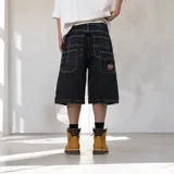 Bermuda baggy de denim negro con costuras en contraste blancas, bolsillos traseros grandes y un parche bordado en forma de estrella con la inscripción 'Venefo'.