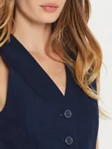 Chaleco azul marino con rayas diplomáticas verticales, cuello en V y cierre frontal con botones.