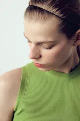 Top crop de tejido de punto color beige claro, con cuello redondo y manga sisa. Presenta acabados en rib en el cuello, sisas y bajo.