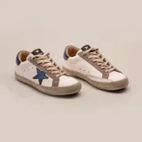 Zapatillas bajas de cuero vacuno color blanco, con estrella azul metalizada en el lateral, detalles en gamuza color aluminio y contrafuerte azul metalizado.