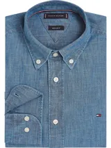 Camisa de chambray celeste de puro algodón, corte regular, con cuello abotonado, puños redondeados con dos botones y logo de Tommy Hilfiger bordado en el pecho.