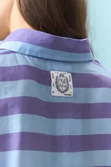 Camisa de algodón con diseño de rayas multicolor en tonos azul, amarillo y rojo. Presenta cuello clásico, cierre frontal con botones y mangas largas.