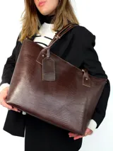 Cartera tipo tote de cuero genuino color marrón oscuro con textura de reptil. Cuenta con doble asa de hombro, cierre superior y un dije colgante de cuero a tono.