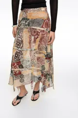 Falda midi de corte irregular con vuelo, confeccionada en viscosa. Presenta cierre lateral con cremallera invisible y tiras desflecadas que aportan movimiento y textura, con diseño estampado tipo patchwork.