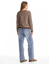 Cardigan de punto con textura tipo tweed, color marrón con detalles en tono oscuro. Presenta cuello redondo, cierre frontal con botones metálicos y dos bolsillos decorativos en la parte inferior.