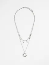 Collar plateado de doble cadena con dijes colgantes en forma de hojas y un dije circular.