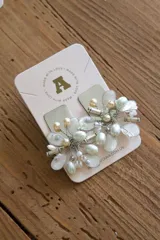 Aros colgantes plateados con forma de flor, adornados con perlas blancas y doradas.