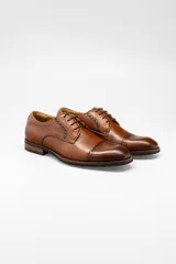 Zapato de vestir acordonado color marrón, de cuero liso, con detalle de perforaciones en la puntera y en los laterales.