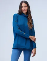 Polera azul con cuello alto, mangas largas y detalle de botones en los puños.