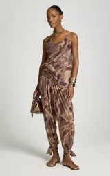 Pantalon balloon de tul con estampado abstracto en tonos marrones y beige, pretina ancha fruncida, forro interior y bajos ajustados con tiras para atar en los tobillos.