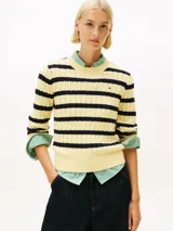 Sweater de punto de algodón orgánico con cuello redondo, diseño de rayas horizontales en amarillo y azul oscuro, y detalle de tejido de cable. Presenta el logo bordado en el pecho de la marca Tommy Hilfiger.