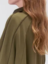 Buzo verde militar de algodón suave, de calce oversize, con cuello alto y cierre frontal parcial metalizado. Cuenta con bolsillos laterales con cierre y puños y ruedo elastizados.