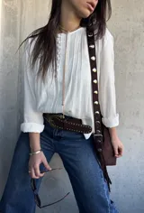 Blusa oversize de color blanco con diseño romántico y bohemio, confeccionada con detalles de encaje y botones forrados en el frente. Cuenta con mangas largas.