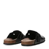 Zueco negro de mujer con suela de goma negra y plantilla de corcho. Presenta una tira ancha ajustable con hebilla metálica sobre el empeine.