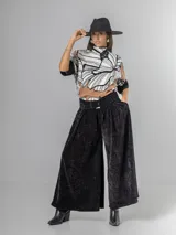 Pantalón tipo palazzo de corte oversized, confeccionado en tela con textura aterciopelada en color negro. Presenta cintura alta con pinzas, bolsillos laterales y un cinturón ancho integrado con hebilla al tono.