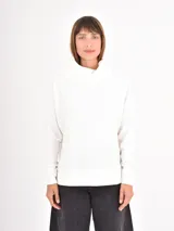 Polera de tejido de punto con textura acanalada, color blanco, de corte holgado, cuello alto tipo tortuga y mangas largas con puños ajustados.