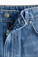 Short de denim de algodón rígido, con diseño de tiro alto y cinco bolsillos. Presenta lavado azul clásico y dobladillo deshilachado.