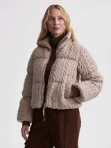 Campera puffer beige con cuello alto acanalado, cierre frontal con cremallera y bolsillos laterales.