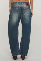 Jeans de tiro bajo confeccionados en denim 100% algodón, con diseño de pierna curva y sutiles desgastes en tono azul vintage.
