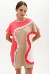Vestido corto de algodón con diseño de bloques de color en tonos azul y celeste. Presenta un corte relajado, cuello redondo, mangas cortas y detalles de volados aplicados en forma curva a lo largo de la prenda.