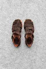 Sandalias cangrejeras de gamuza color marrón, con diseño de tiras anchas entrelazadas, punta redonda y talón cerrado con tira ajustable al tobillo.