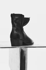Bota de piel color negro con acabado abatanado, caña corta, punta fina y tacón cuadrado a tono.