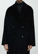 Abrigo largo de diseño oversize con doble botonadura, cuello con solapas de muesca y hombros caídos. Cuenta con dos bolsillos laterales y abertura posterior en el bajo.
