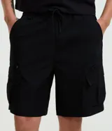 Bermuda cargo baggy negra, confeccionada en poliéster con cintura elástica, cordón ajustable y bolsillos laterales con cierre de cremallera.