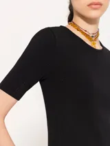 Top tejido en hilado frío color verde militar, con calce al cuerpo, mangas cortas y abertura en la espalda que se ata en el cuello.