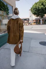 Chaqueta larga de piel color marrón, con cuello solapa, manga larga, bolsillos delanteros de plastrón y cierre frontal con botones.