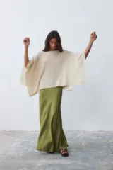 Poncho tejido color crudo, con cuello bote y mangas 3/4.