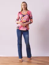 Remera de algodón estampada con flores en tonos celeste, azul y verde, sobre fondo negro. Tiene mangas 3/4 y escote cuadrado.