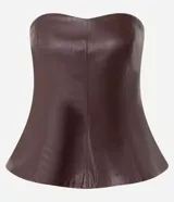 Blusa peplum sin breteles confeccionada en PU color bordó, con escote corazón y cierre posterior por cremallera. Presenta un diseño estructurado con ruedo evasé.